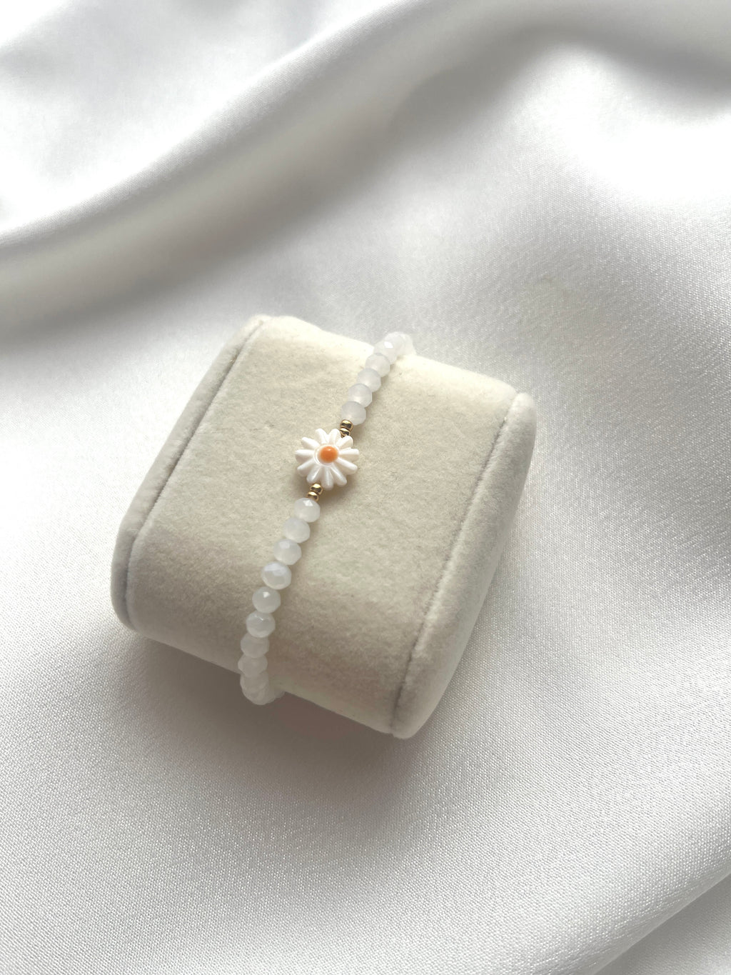 Perlenarmband aus weißen Kristallperlen und einer Perlmutt-Gänseblüme