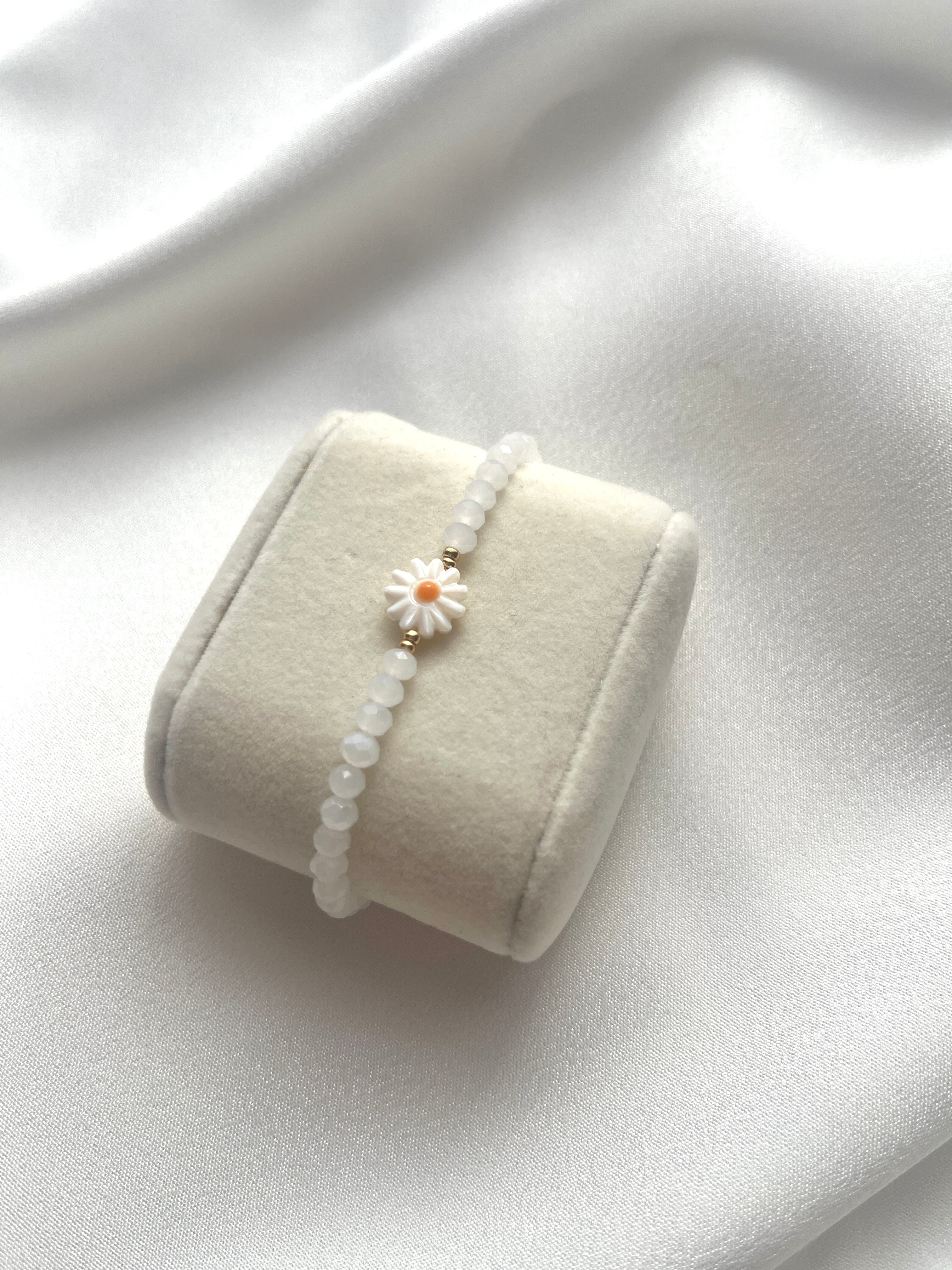 Perlenarmband aus weißen Kristallperlen und einer Perlmutt-Gänseblüme
