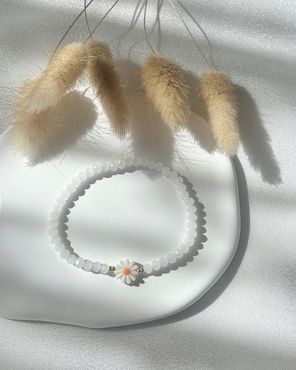 Perlenarmband aus weißen Kristallperlen und einer Perlmutt-Gänseblüme
