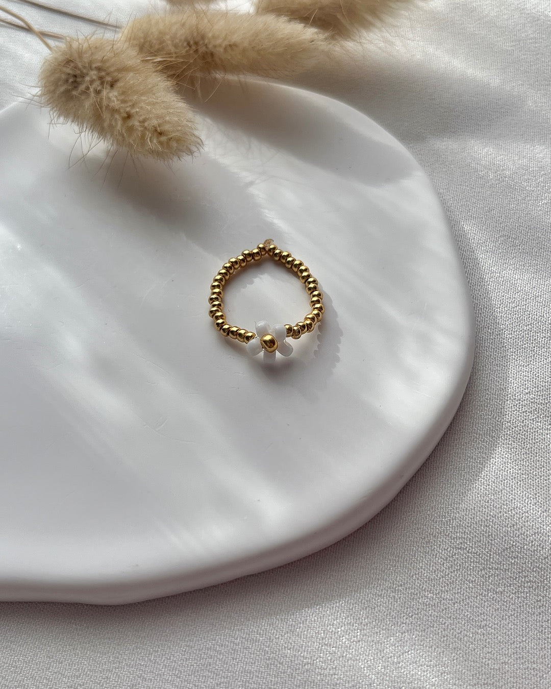 Perlenring aus goldenen Perlen & weißer Blume