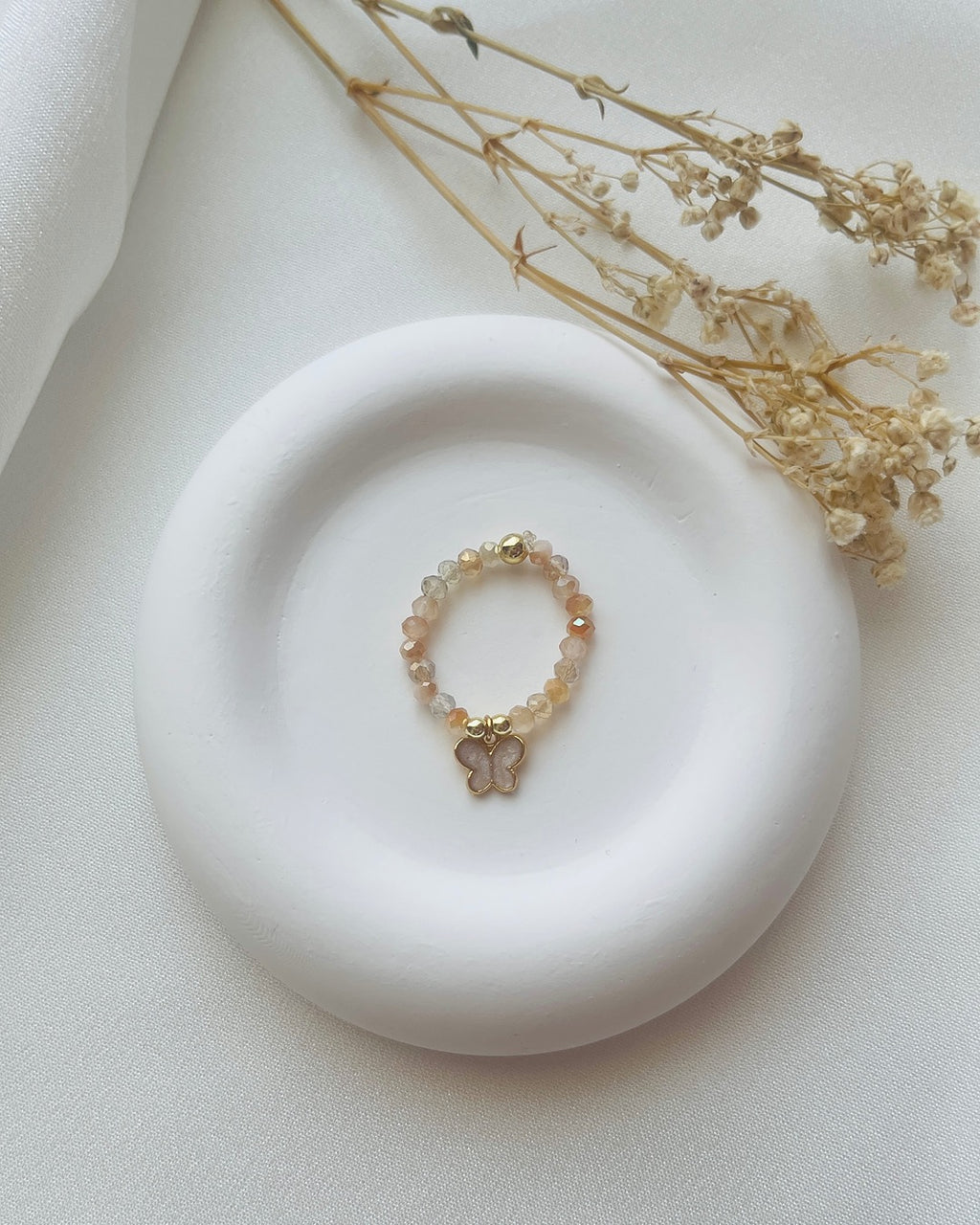 Perlenring aus beigefarbene Perlen & Schmetterling-Charm