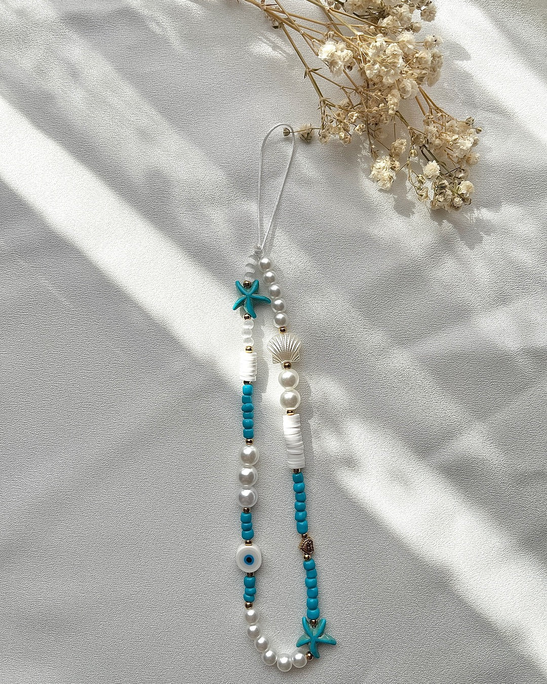 Handykette aus türkis-blauen Perlen, Seesternen & Nazar