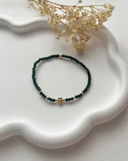 Perlenarmband in Smaragdgrün mit einer goldenen Blume