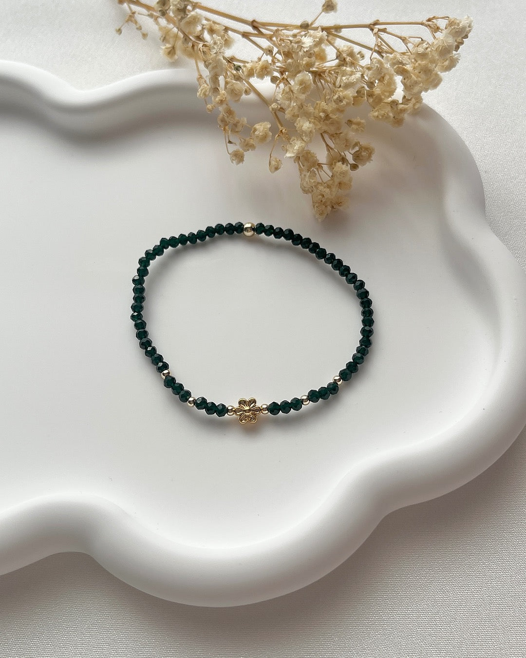 Perlenarmband in Smaragdgrün mit einer goldenen Blume